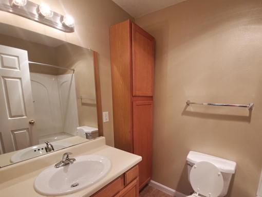 A white toilet sits in a bathroom with a sink and mirror.