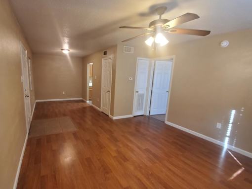 A long hallway with wood floors and a ceiling fan.