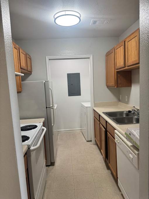 A small kitchen with a microwave, oven, and a fan.