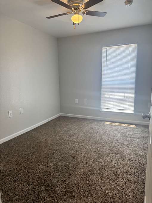 A room with a ceiling fan and a window.