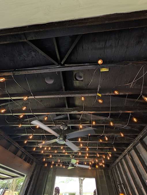 A ceiling fan is hanging from the ceiling with lights strung up around it.