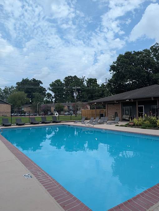 A large swimming pool with a red brick border.
