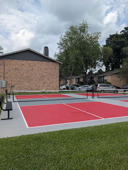 A red and white basketball court in front of a brick building.