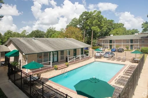 A pool surrounded by a black fence with green umbrellas.