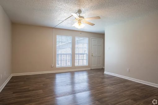 A room with a ceiling fan and wooden flooring.