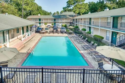 A swimming pool surrounded by a black fence and chairs.