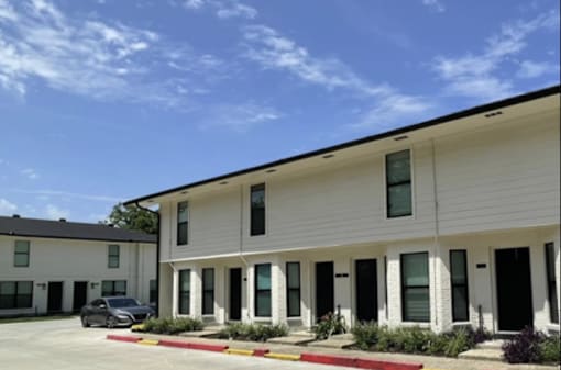A white building with a black car parked in front.