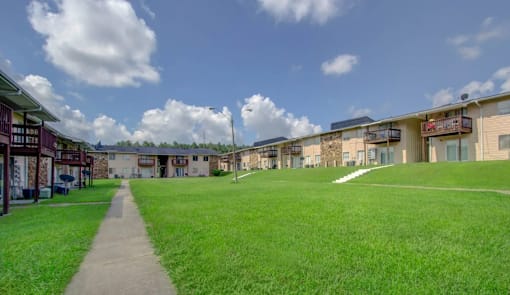 A grassy area in front of a building with a walkway leading to it.