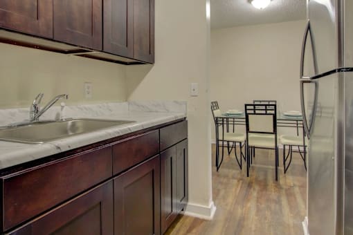 A kitchen with a white sink and brown cabinets.