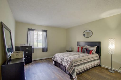 A bedroom with a bed, dresser, and mirror.