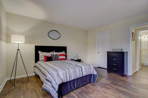 A bedroom with a bed, nightstand, and lamp.