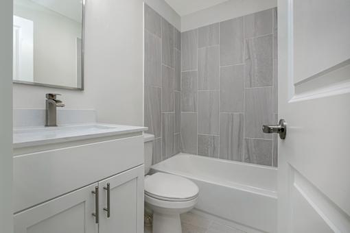 A white bathroom with a toilet, sink, and tiled shower.