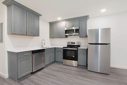 A modern kitchen with stainless steel appliances and grey cabinets.