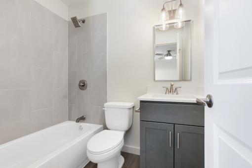 A white toilet sits next to a white bathtub in a bathroom.