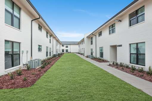 A long white building with a green lawn in front.