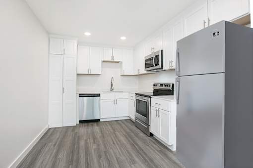 A kitchen with white cabinets and a grey refrigerator.