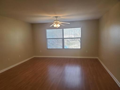 A room with a ceiling fan and a window with blinds.