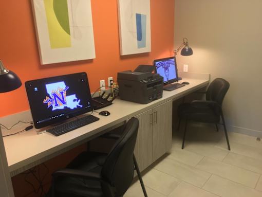 A workspace with a laptop, a desktop computer, and a printer on a white desk.