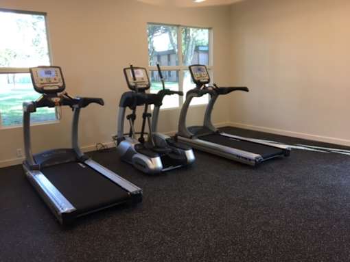 Three exercise machines are lined up in a room.