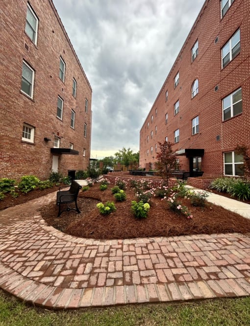 a courtyard with a bench and a brick building