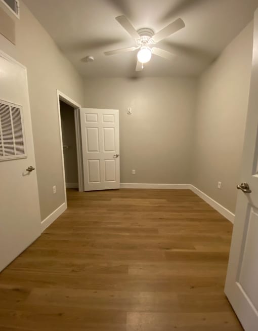 a bedroom with a wood floor and a ceiling fan