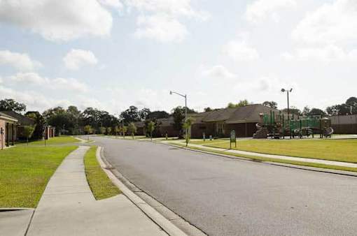 A street with houses on one side and a park on the other.