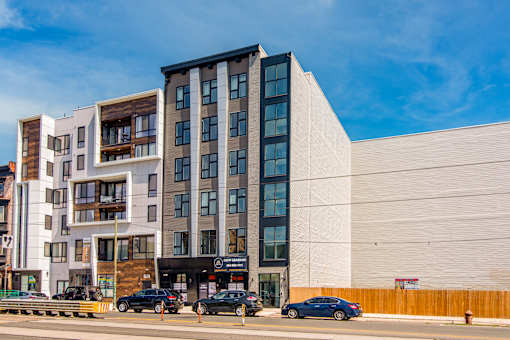 A modern multi-story building with cars parked in front.