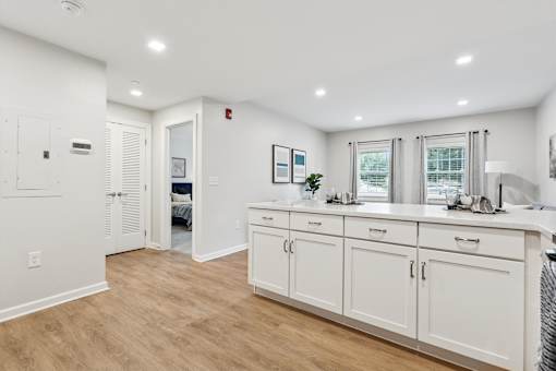 A white kitchen with wood floors and white cabinets at Roosevelt Commons Apartments, Pennsylvania 19152