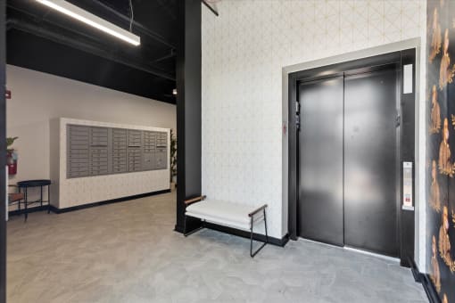 a bench sits in front of a pair of black doors