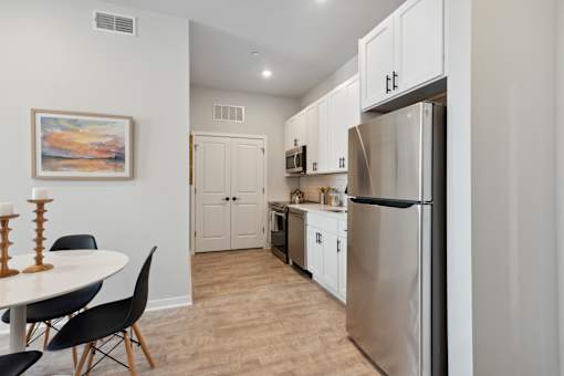 A kitchen with a refrigerator, table and chairs.