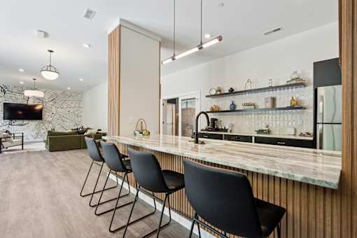 A kitchen with a marble countertop and black chairs.