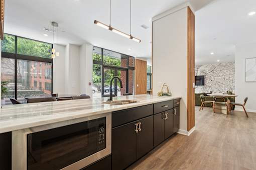 A modern kitchen with dark wood cabinets and a marble countertop.