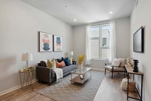 A living room with a grey couch, a coffee table, and a large window.