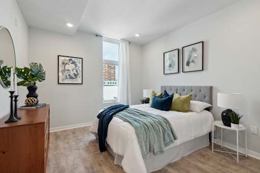 A bedroom with a bed, nightstand, and a mirror.