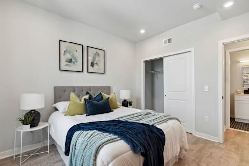 A bedroom with a bed, two lamps, a nightstand, and two pictures on the wall.