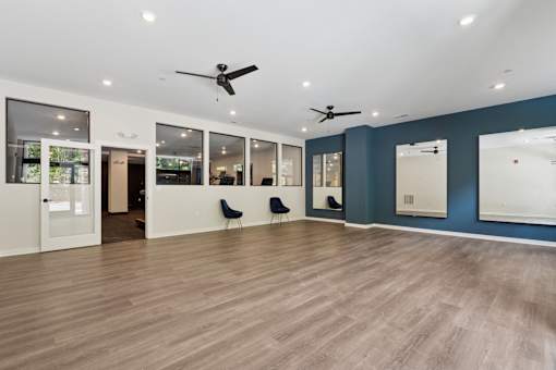 A spacious room with wooden floors and ceiling fans.