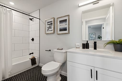 A white bathroom with a black and white tiled floor.