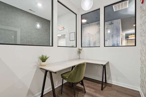 A white desk with a green chair in front of a mirrored wall.