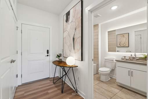 A bathroom with a toilet, sink, and a painting on the wall.