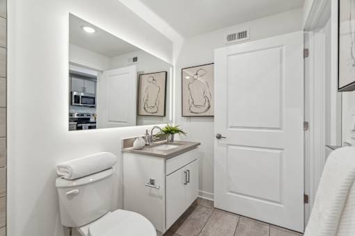 A white bathroom with a toilet, sink, and mirror.
