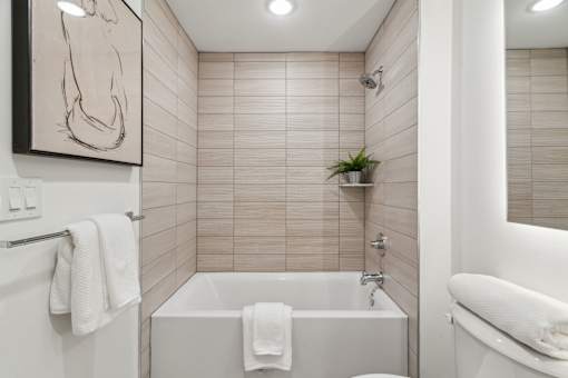 A white bathroom with a tub and a towel hanging on the side.