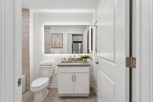 A white bathroom with a toilet, sink, and cabinet.