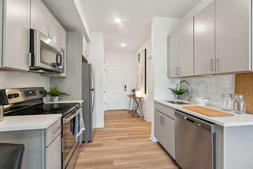 A modern kitchen with stainless steel appliances and wooden floors.