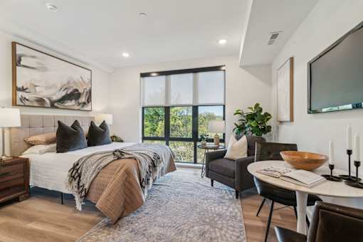 A bedroom with a large bed and a chair.