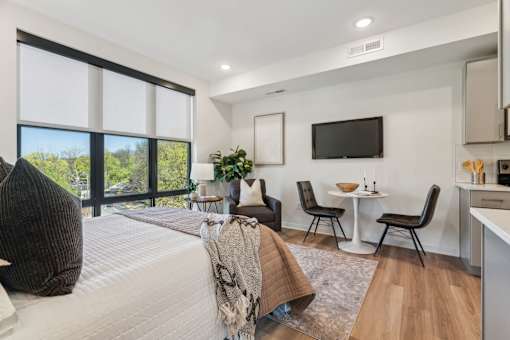 A modern bedroom with a large bed and a flat screen TV mounted on the wall.
