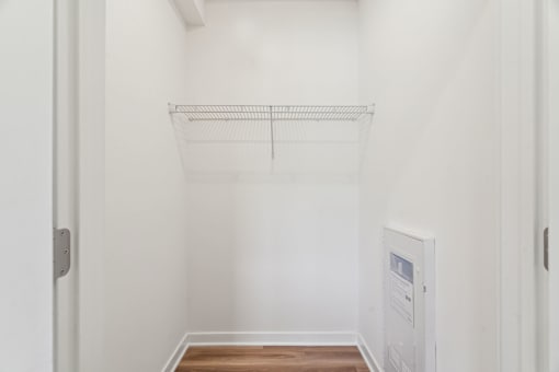 A white wall with a shelf and a door.