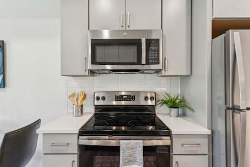 A modern kitchen with a stove, microwave, and refrigerator.