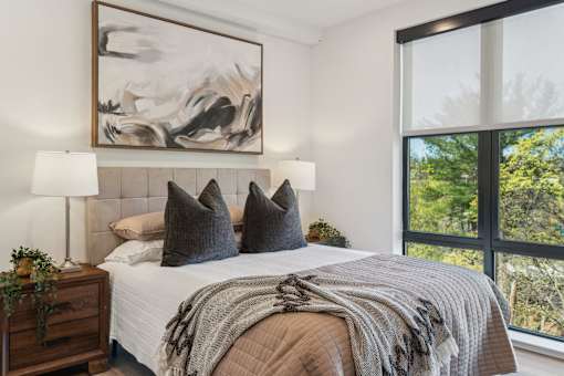A bedroom with a large bed, a lamp, and a painting on the wall.