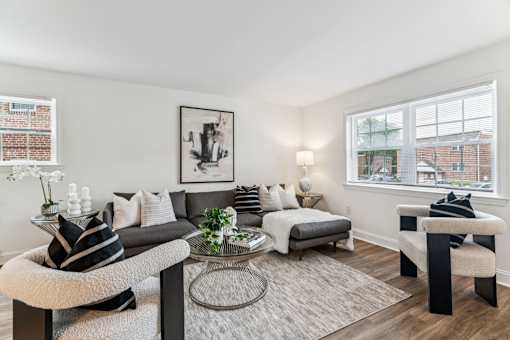 A living room with a grey couch, a white chair, and a black and white striped pillow.
