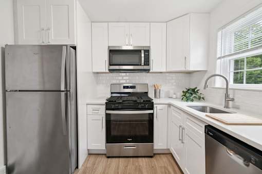 A modern kitchen with a refrigerator, microwave, oven, and sink.